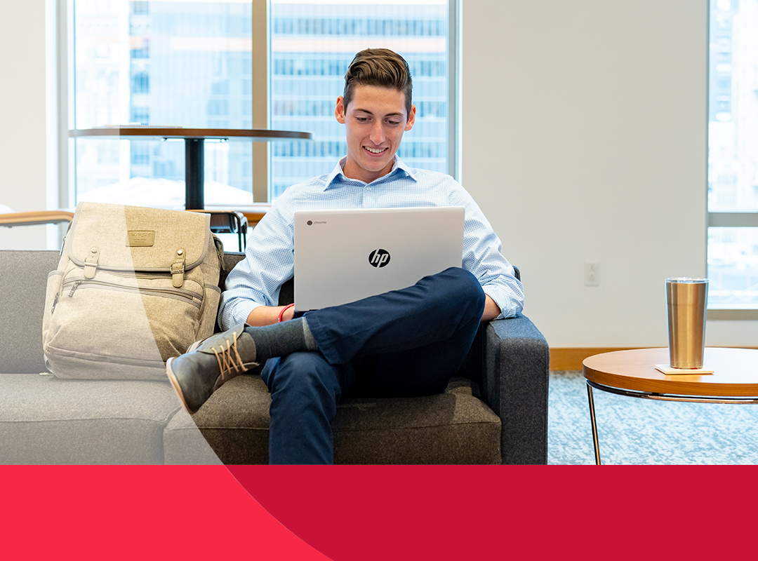 A student in a lounge studying on a laptop.